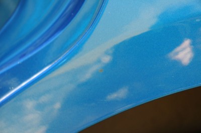 Hrdzavy flek na lavom zadnom blatniku bez znamky skrabnutia alebo odlupenia laku