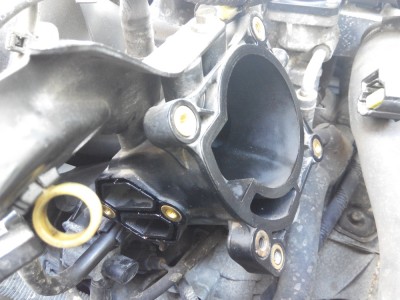 Na pravé straně otvor pro škrtící klapnu, na levé straně otvor na volnoběžný ventil.. Klapka i ventil mají gumové těsnění, lze ošetřit silikonovým olejem a znovu použít...